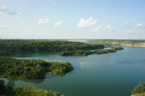 Breiter ruhiger Fluss mit waldbewachsenen Hängen und Inseln unter blauem Himmel