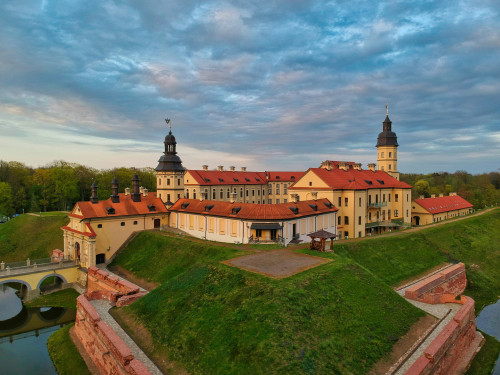 Schlossanlage auf grünem Hügel unter blauem Himmel